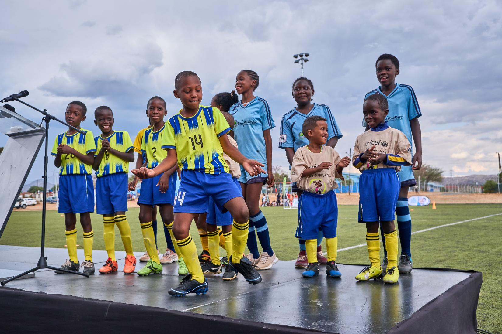Young soccer players dance on a stage in their soccer uniforms