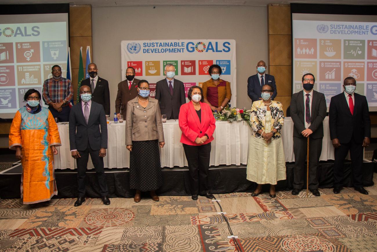 Image shows two rows of dignitaries standing infront of an image of the UN's SDGs