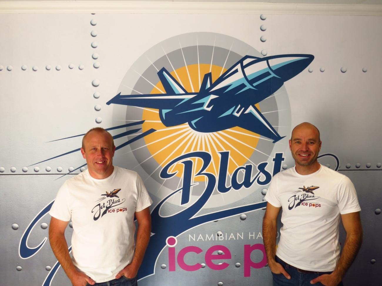 Two men in white shirts standing in front of the Jet Blast Ice Pops logo