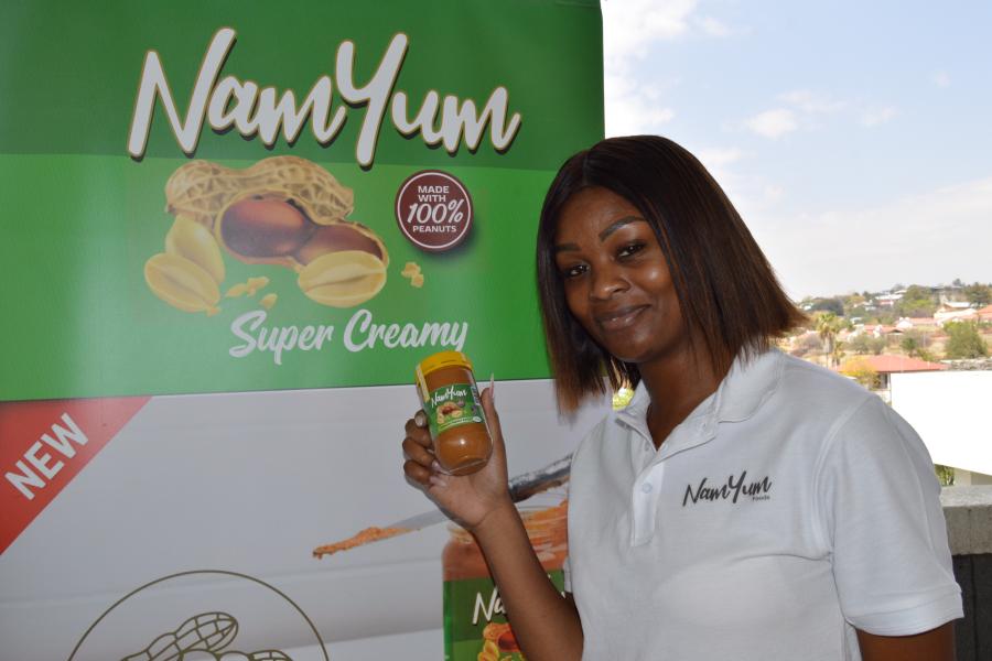 Image of a woman holding a jar of peanut butter infront of a 'NamYum' banner