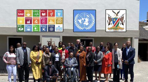 Officials gather for a photo. The UN logo and Namibian coat of arms are imposed above. 