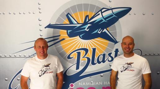 Two men in white shirts standing in front of the Jet Blast Ice Pops logo