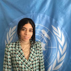 woman standing in front of blue UN flag